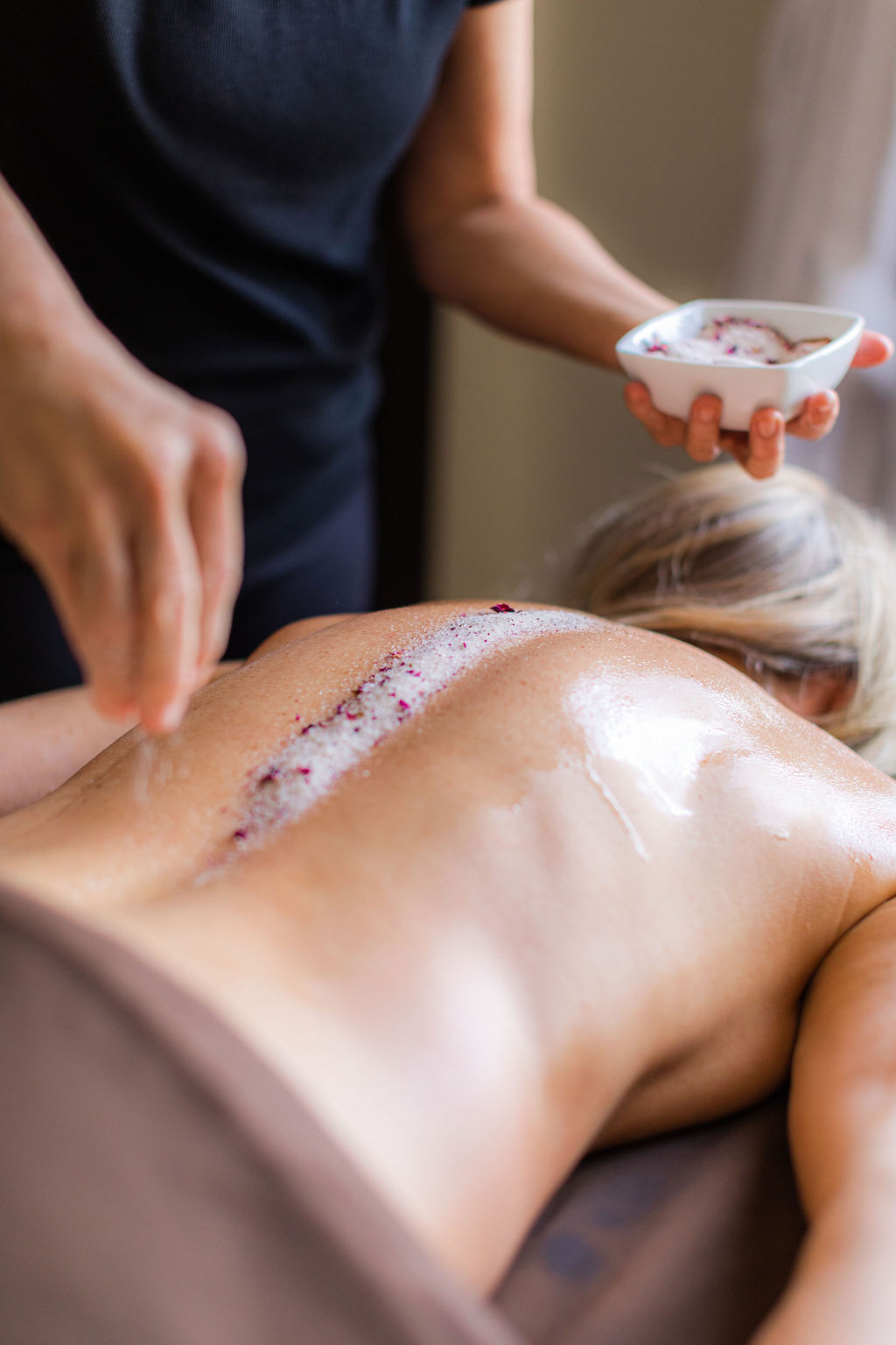 La Vida Spa Massage Add-on, full body exfoliating scrub, therapist sprinkling scrub onto guest spine